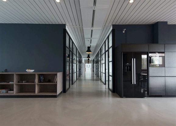 A long hallway with two refrigerators and shelves.