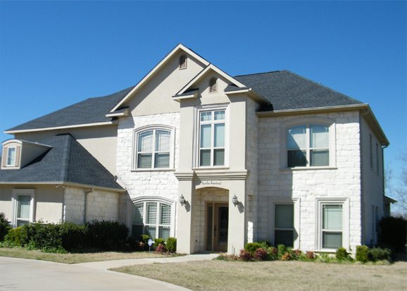 A large white house with black roof and windows.