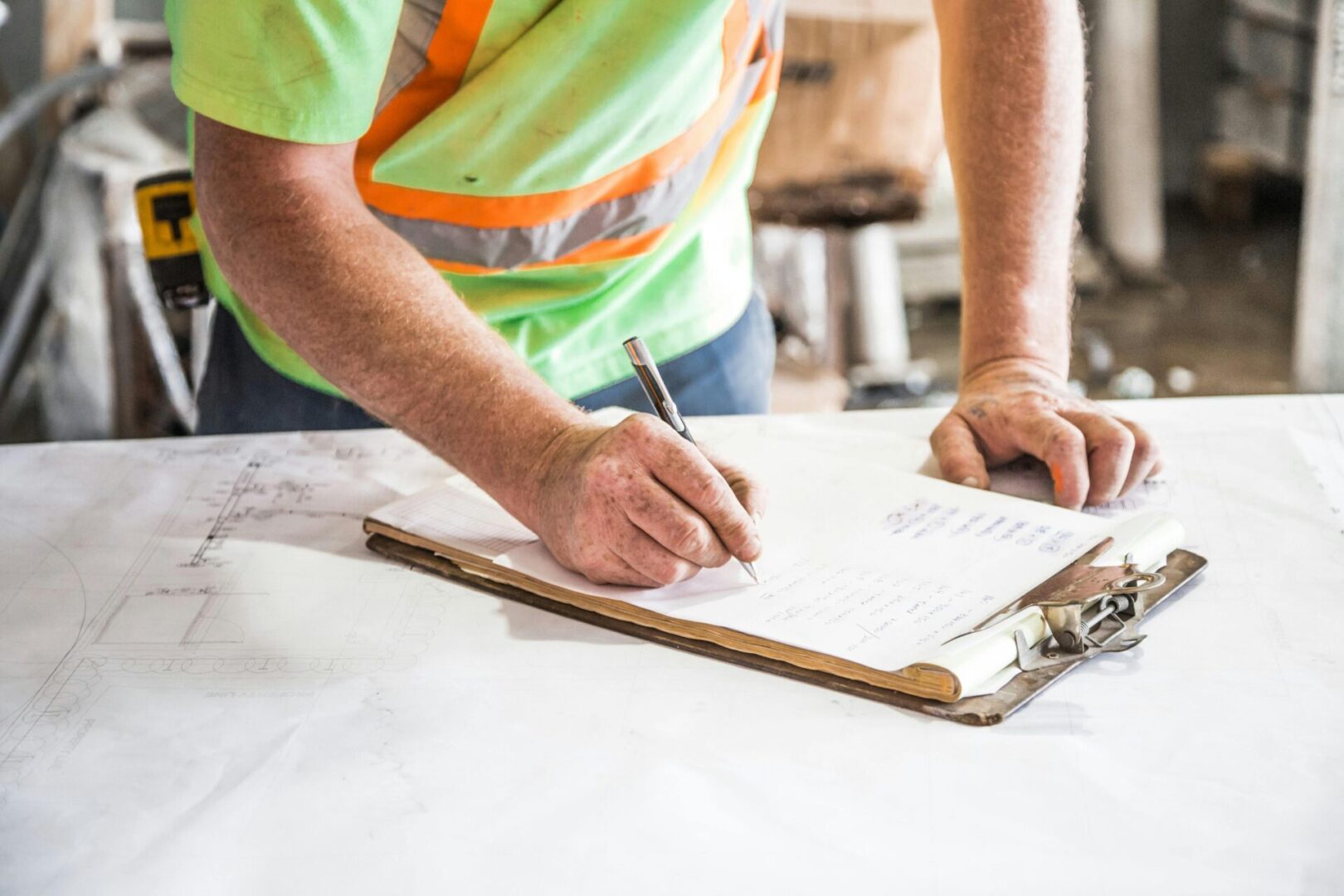 A man writing on paper next to a clipboard.